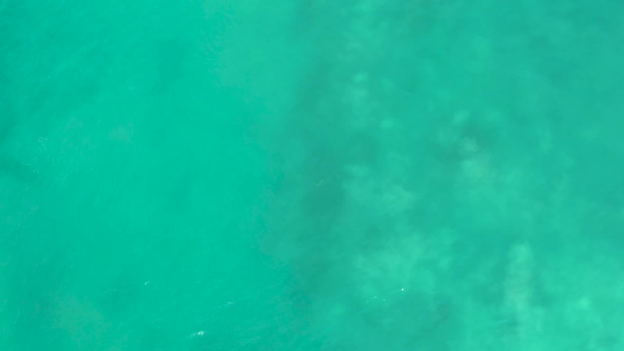 Turquoise water at San Luis Beach East Cape Los Cabos, Mexico, shows cloudy pale seabed patches beneath the surface and no visible people.