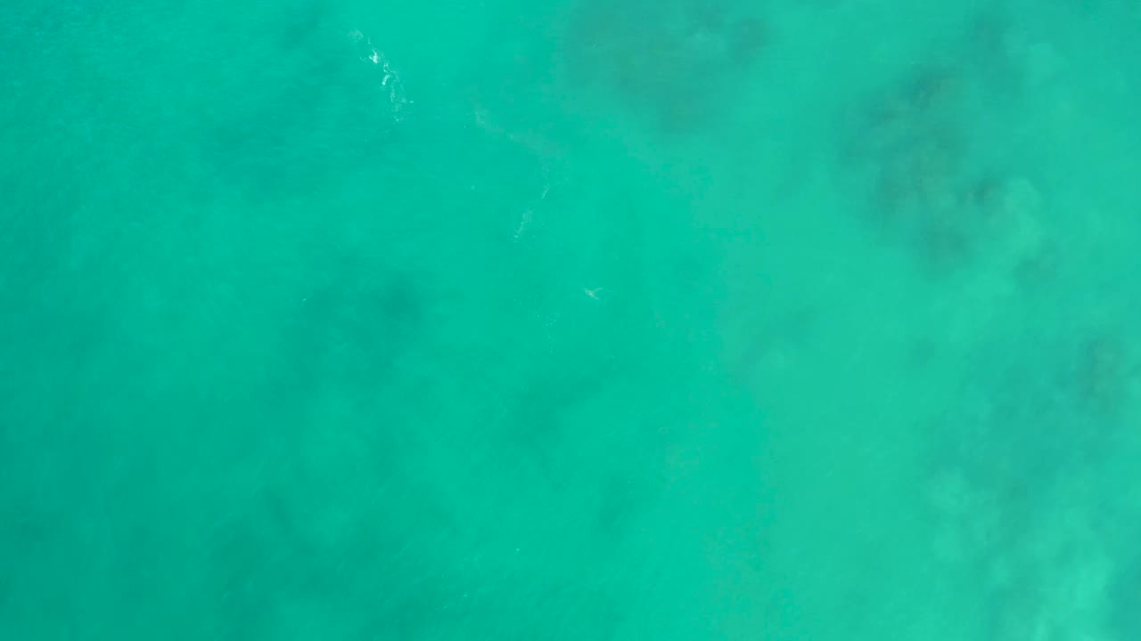 Overhead view of turquoise water at San Luis Beach East Cape Los Cabos, with faint seabed patches beneath the surface and no visible people.