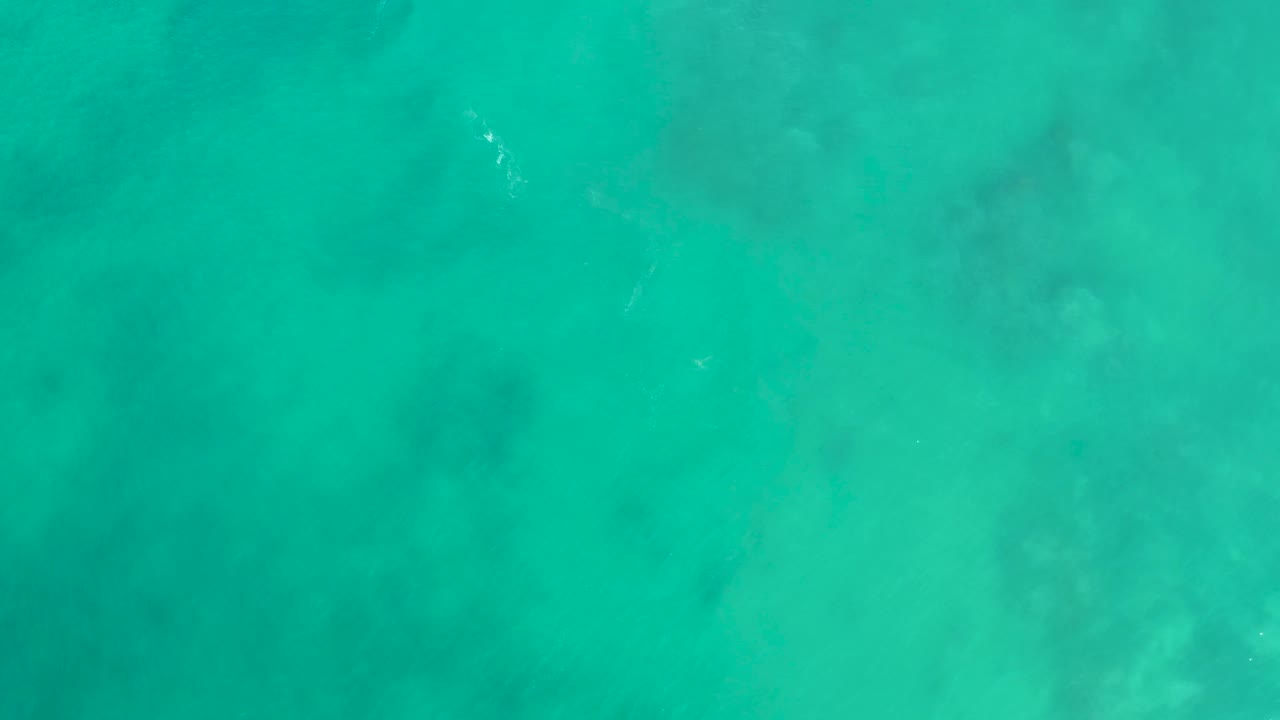 Overhead turquoise ocean water with darker underwater patches.