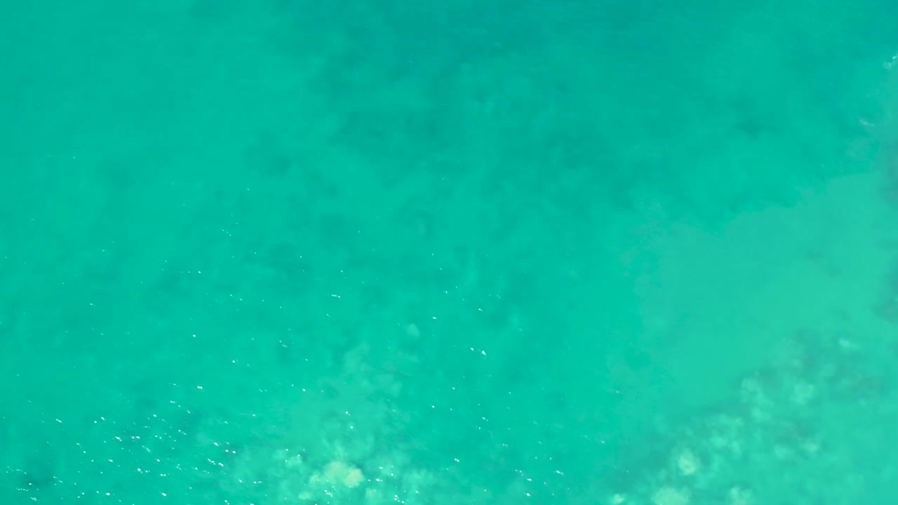 Shallow green-blue ocean with darker underwater shapes