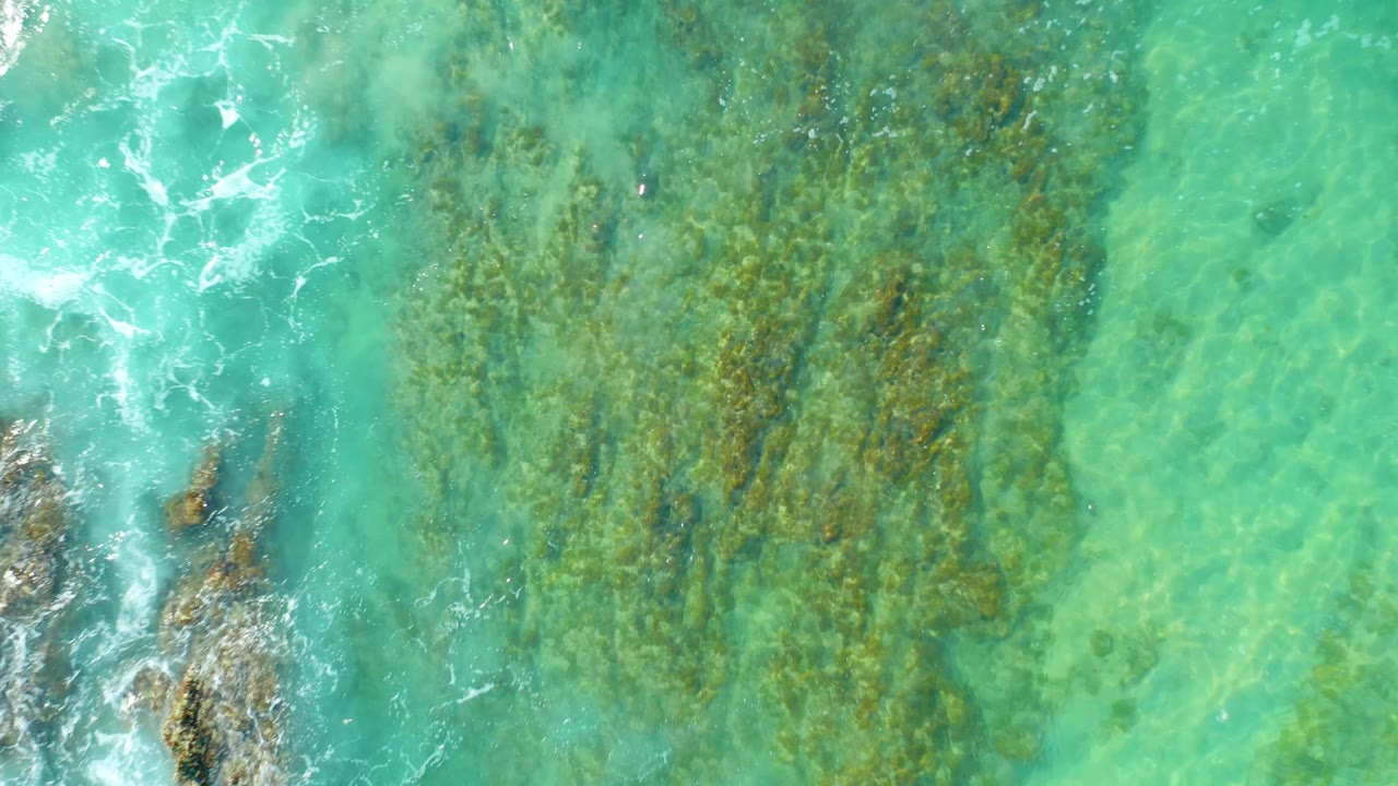 Overhead turquoise water with submerged rocks and light surf.