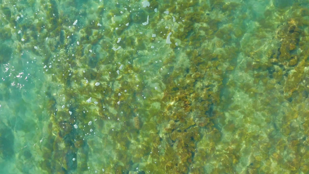 Ripples crossing shallow water above rocks.
