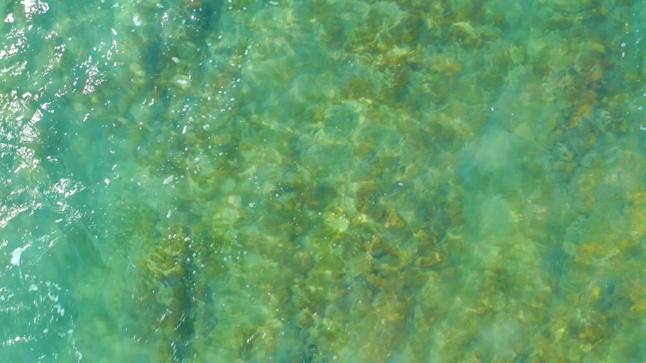 Turquoise shallow ocean water over submerged rocks.
