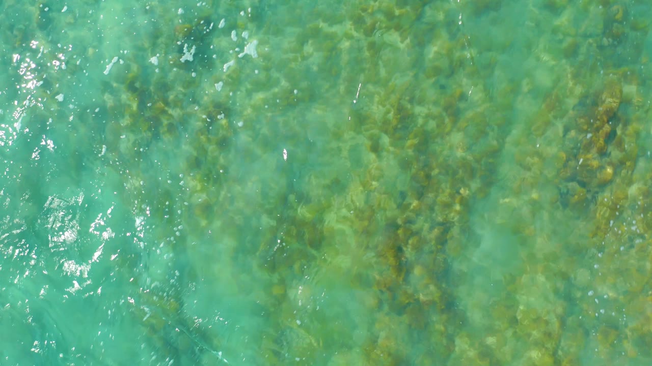 Turquoise water with bright ripples over rocky seabed