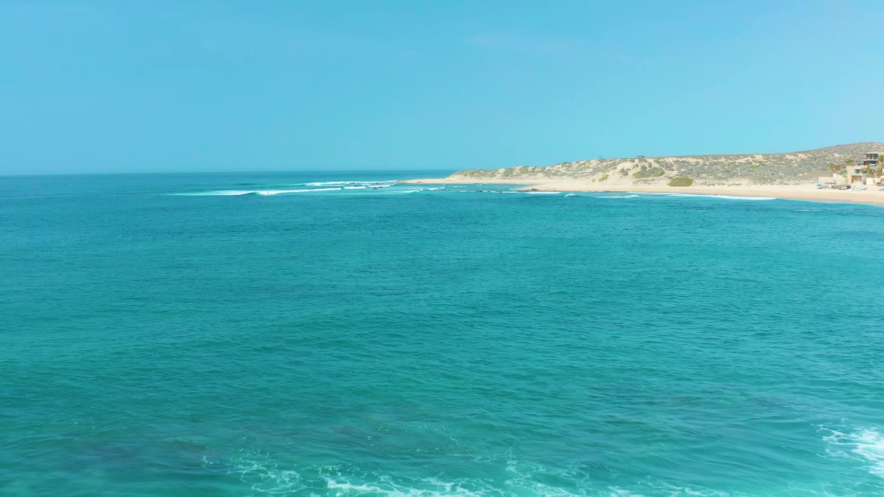 Open turquoise water with white surf lines near a sandy coastline.
