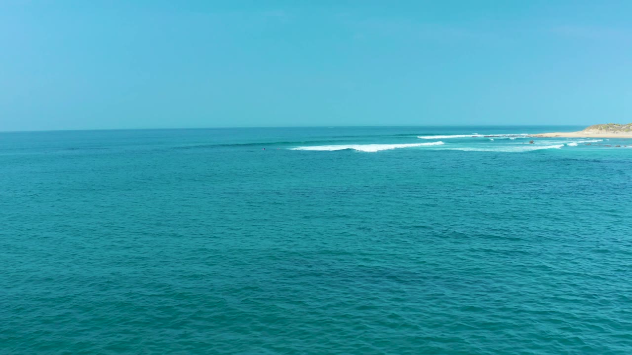 At San Luis Beach in Mexico, blue-green sea spreads across the frame with thin white surf lines near the far shoreline and no visible people.
