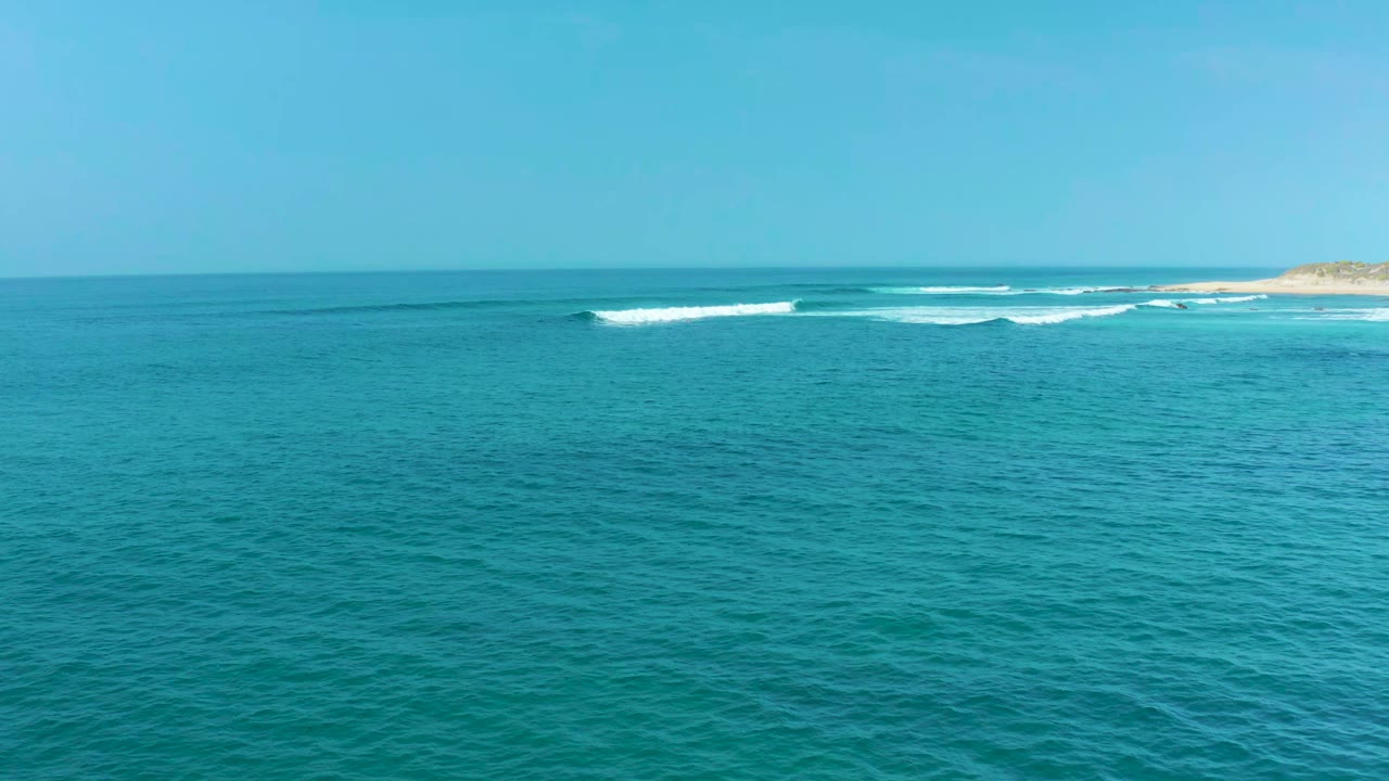 Opening frame of San Luis Beach, East Cape Los Cabos, with blue-green ocean, white surf lines near the distant shore, clear sky, and no visible people.