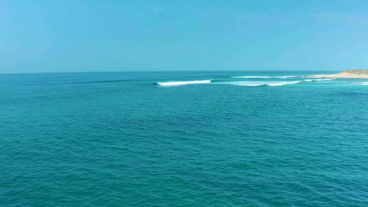 Wide ocean view with a white wave crest forming near the far shore.