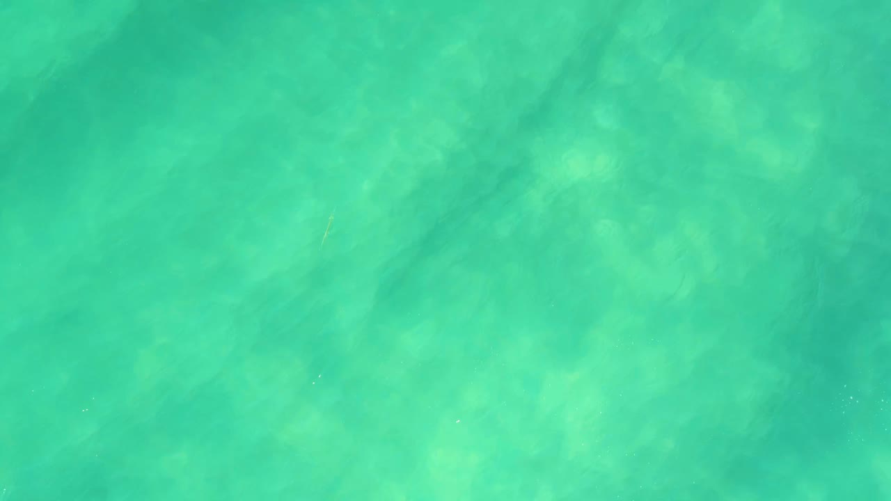 Top-down view of turquoise shallow ocean water in Campestre San Jose del Cabo BCS Mexico, with pale sandy bottom patterns and no visible people.