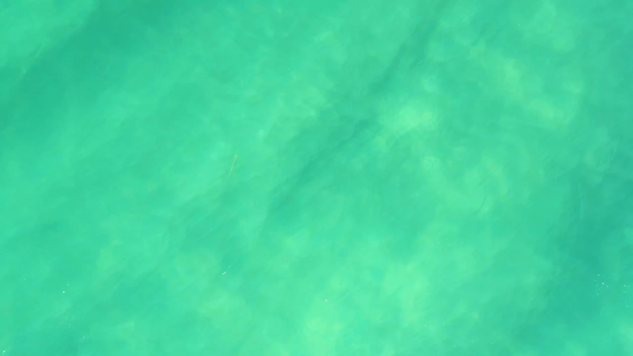 Clear shallow ocean water in Campestre San Jose del Cabo BCS Mexico, with darker ripple streaks crossing the blue-green surface and no visible people.