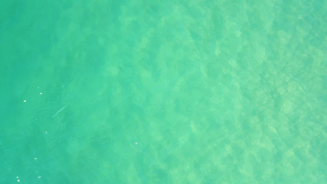 Turquoise shallow water with faint seabed texture and small surface ripples.