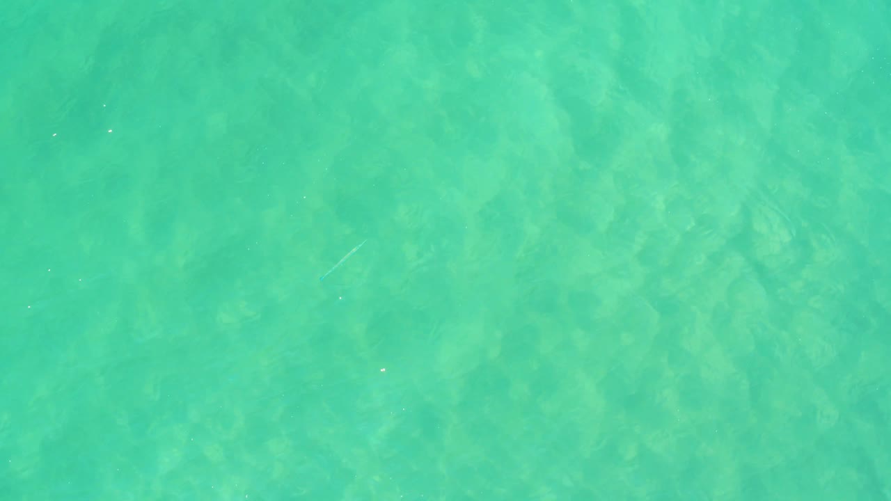 Turquoise water surface with subtle ripple bands.