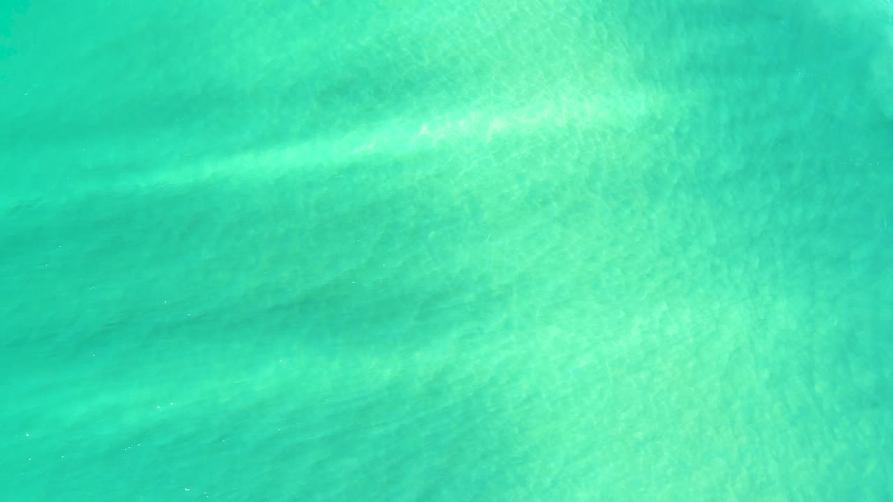 Clear green-blue shallow water in Campestre San Jose Del Cabo BCS Mexico, with a brighter diagonal band of sunlight across the sandy bottom and no visible people.
