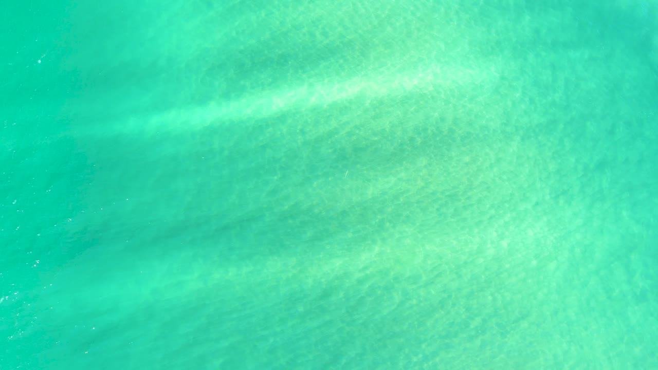 Aqua shallow water in Campestre San Jose Del Cabo BCS Mexico, with a soft sandy floor visible beneath small shimmering surface lines and no visible people.
