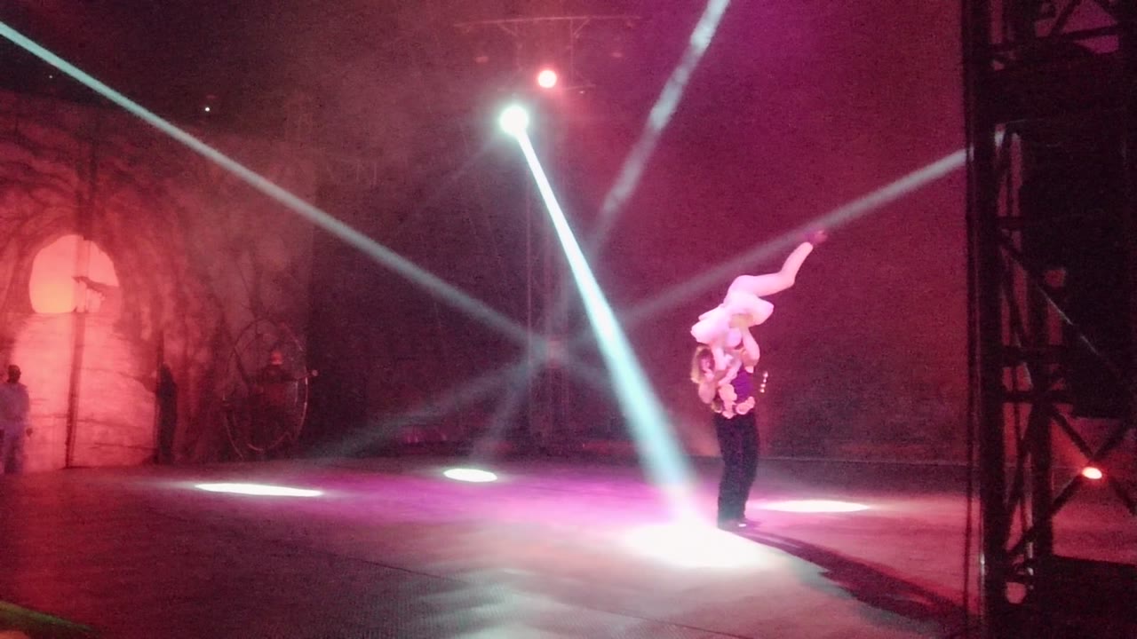 In San Jose del Cabo BCS Mexico, the upper performer extends sideways while the base performer supports the lift near a bright floor spotlight.