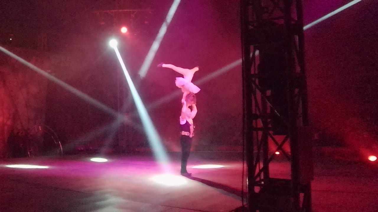 Upper acrobat holds a stretched pose above the base performer