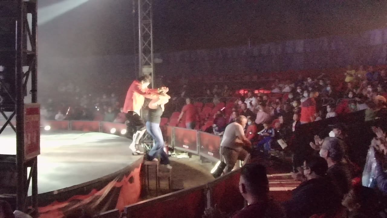 In San Jose del Cabo, Mexico, the red-shirted performer reaches toward a person at the stage edge while the audience fills the background seating.