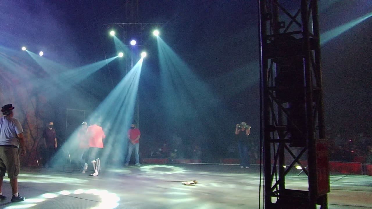 Stage performers move closer beneath crossing beams of light