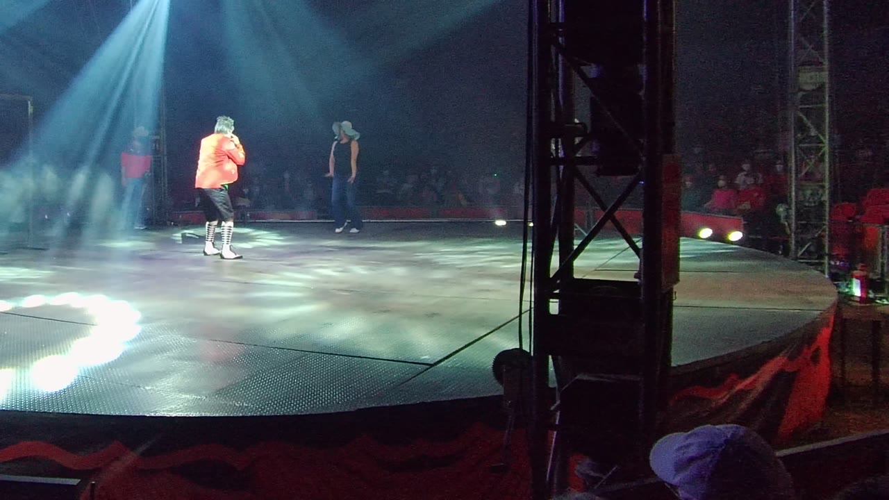 Stage dancer facing a background performer under white light