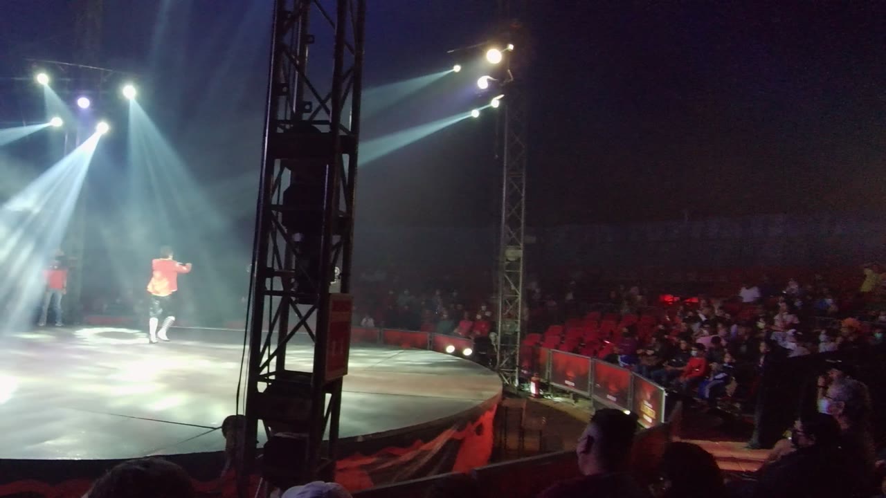 Two red-clad performers on a lit circus stage
