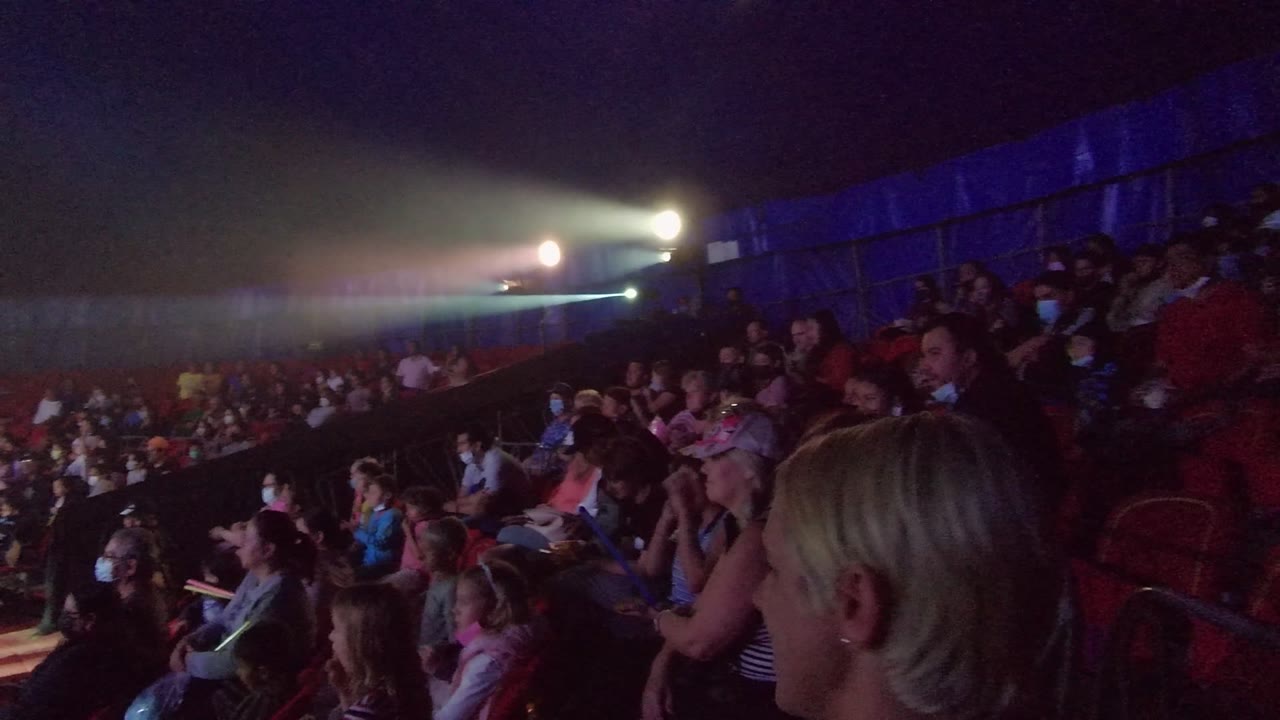 Crowd in red seating with bright spotlights overhead
