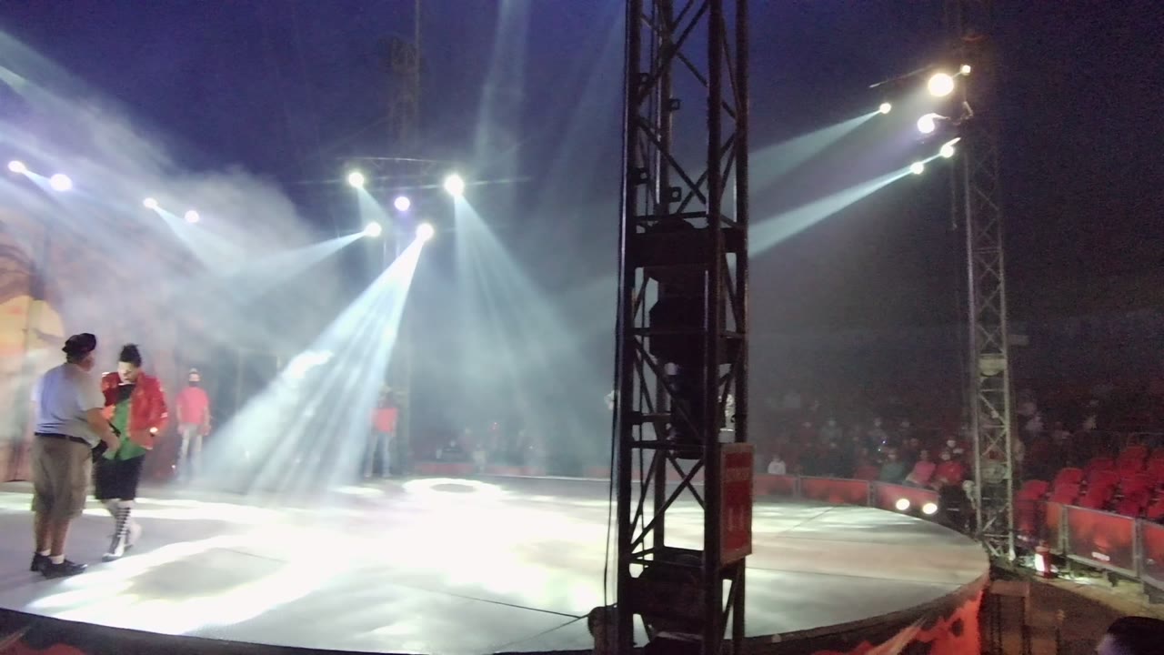 In San Jose Del Cabo BCS Mexico, performers are still visible at the left edge of a stage while white spotlights shine through smoke toward red audience seating.