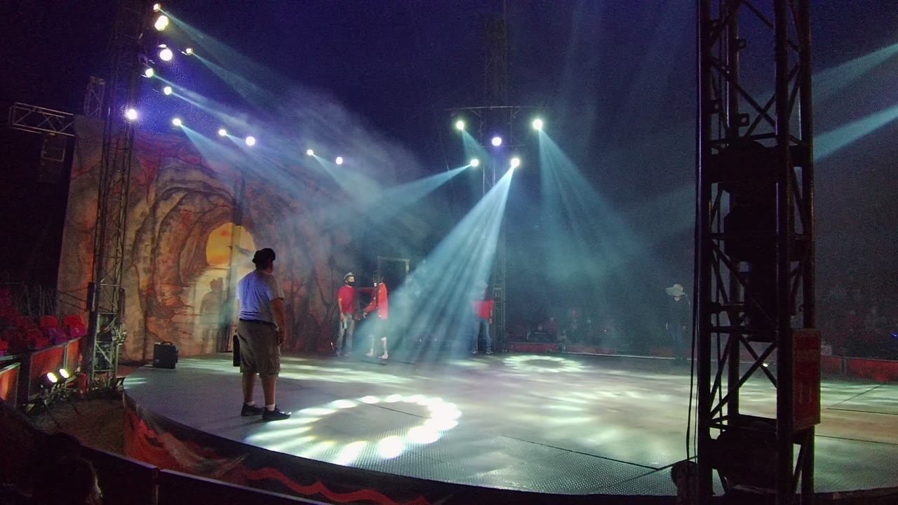 Stage performers under crossing spotlights with smoke over the floor