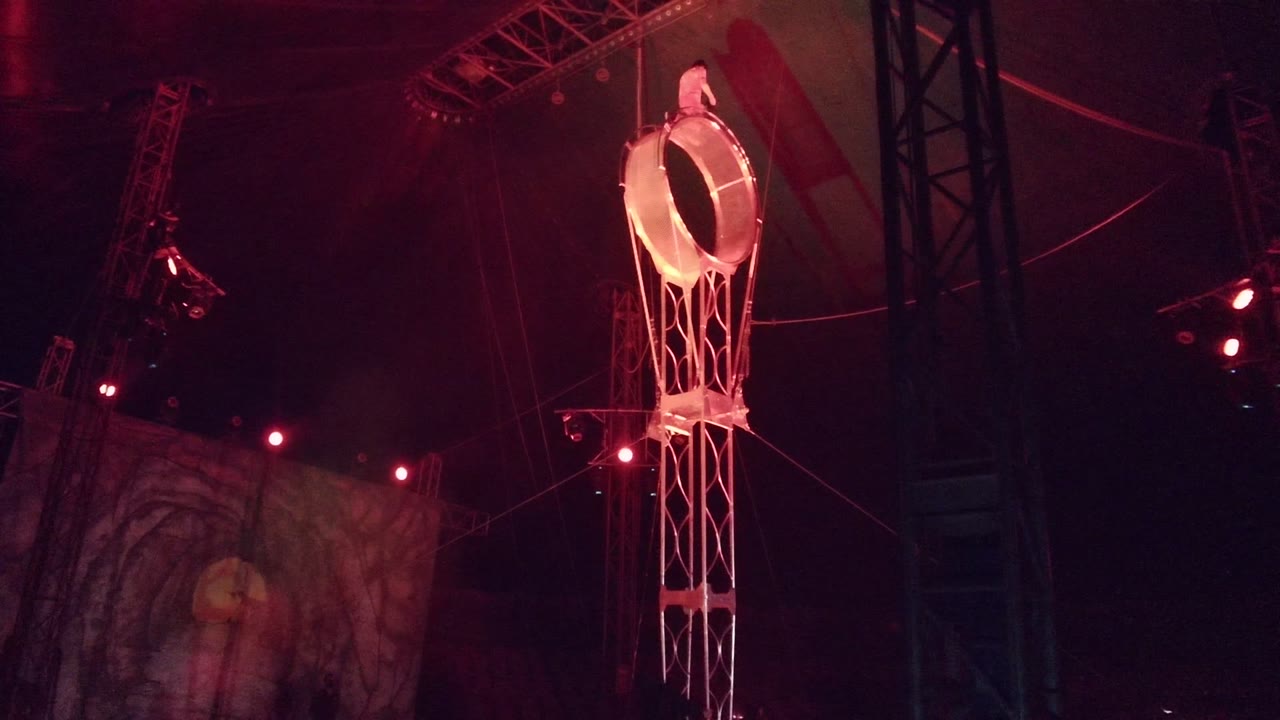 Illuminated ring prop beside dark stage rigging