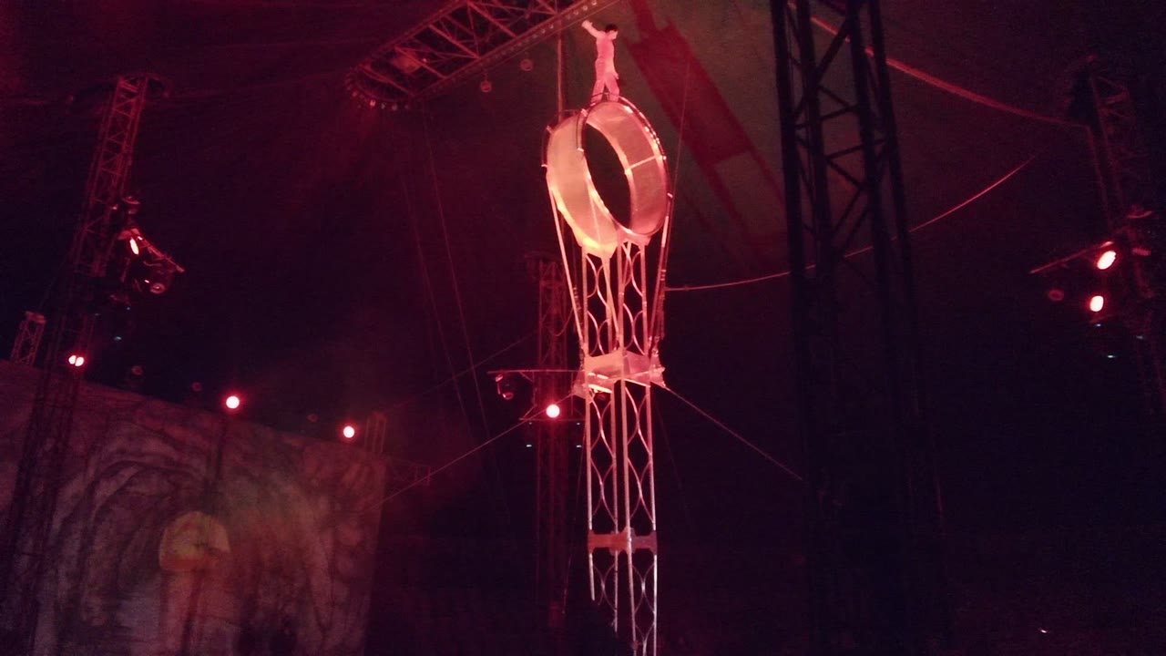 In San Jose Del Cabo BCS Mexico, a small figure stands on the ring's top edge while the suspended structure and red stage lights dominate the dark frame.