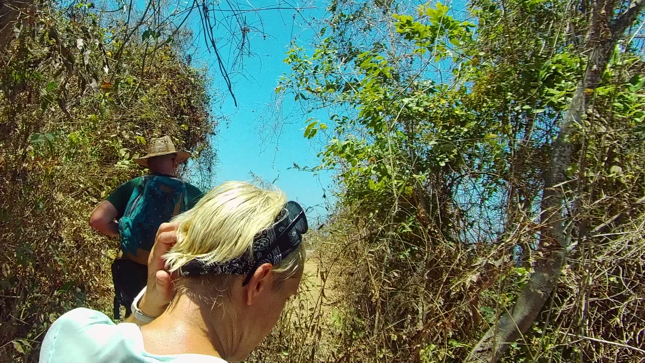 Foreground hiker adjusts hair while another hiker stands ahead on the trail.