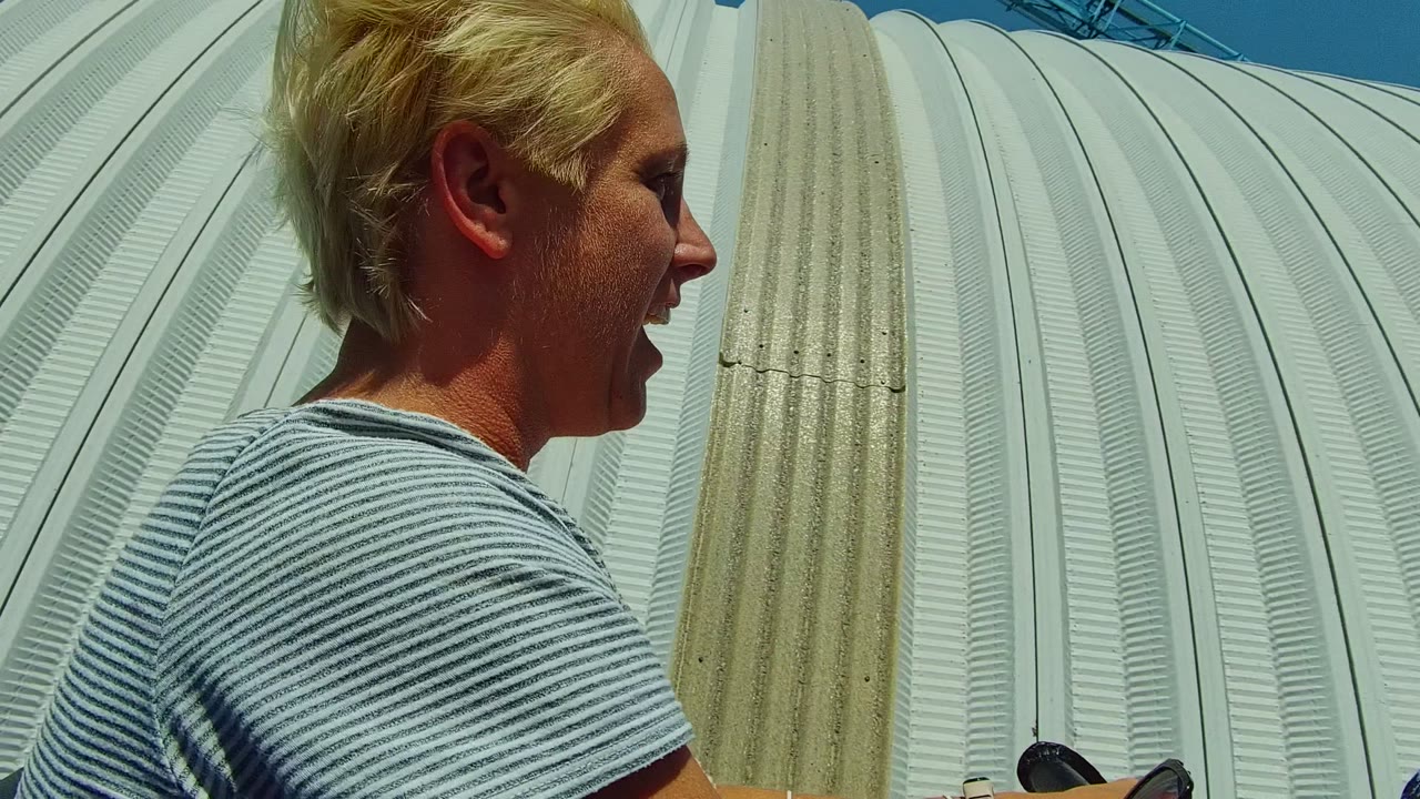 In Guadalajara Mexico, a blond passenger is seen in profile near a white ribbed dome while another rider's head appears in the foreground on an amusement park ride.