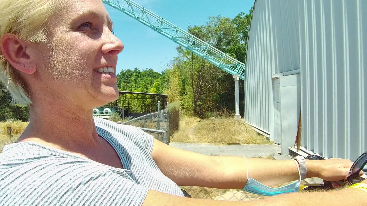 Woman smiling in a moving vehicle near crane and metal building