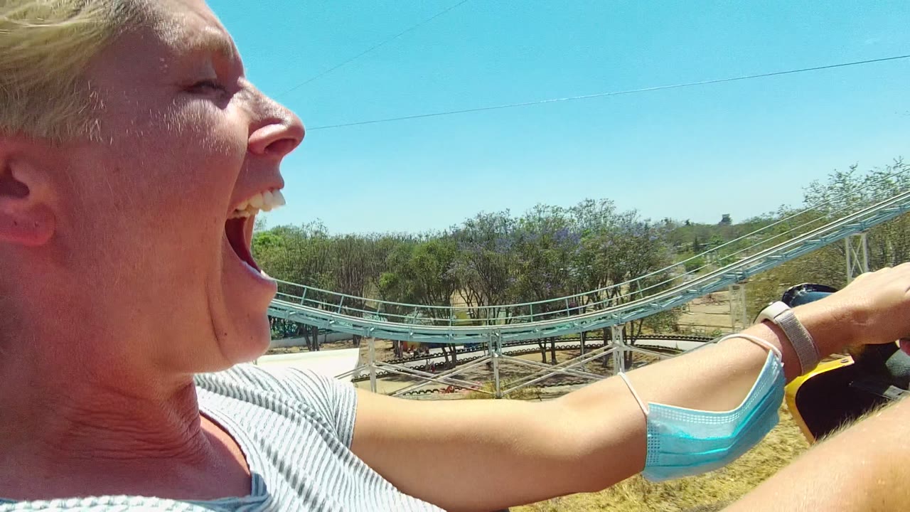 Woman yelling on a roller coaster with her arm extended forward.