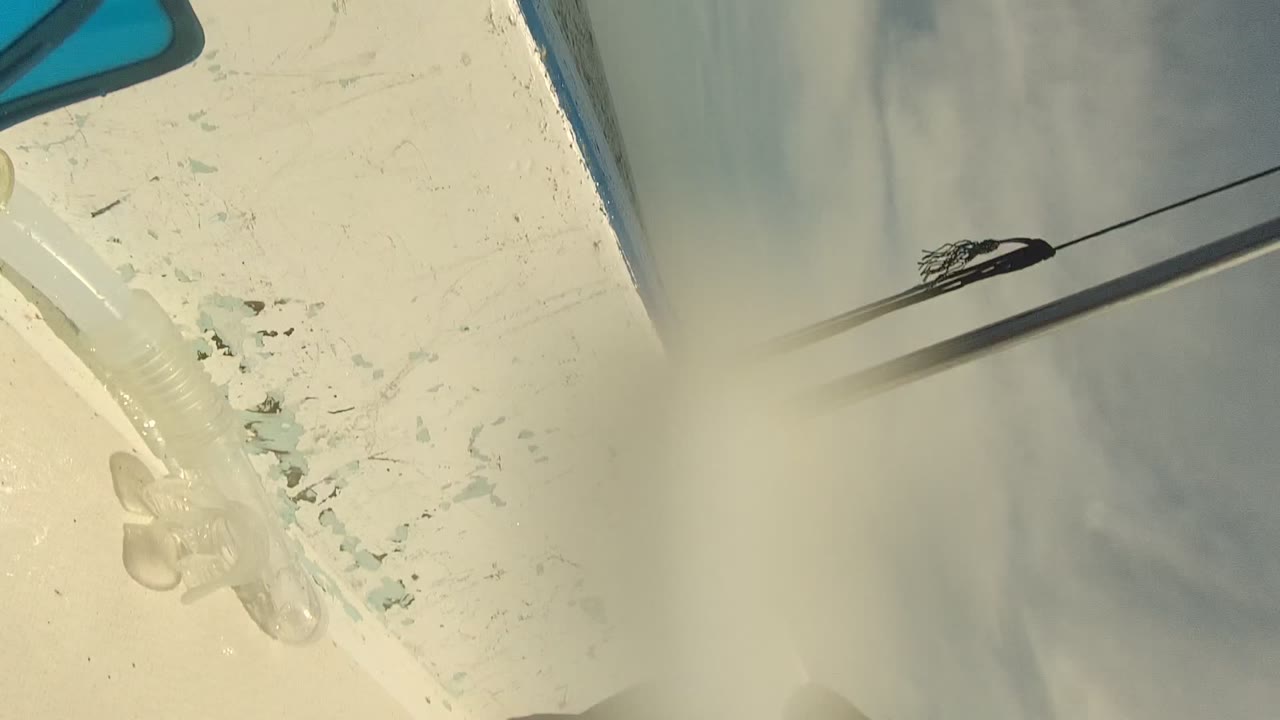 Close tilted view of a white boat deck with chipped paint, pale sky reflection, and surrounding water in Cabo Pulmo, Mexico, with no visible people.
