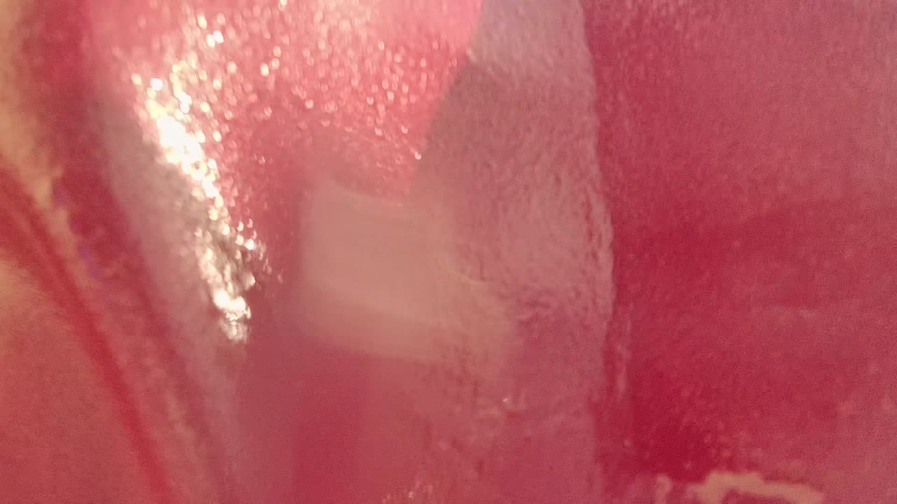 Extreme close-up of red flag fabric in Cabo Pulmo, Mexico, with shiny highlights, tan worn-looking graphic areas, soft haze, and no visible people.