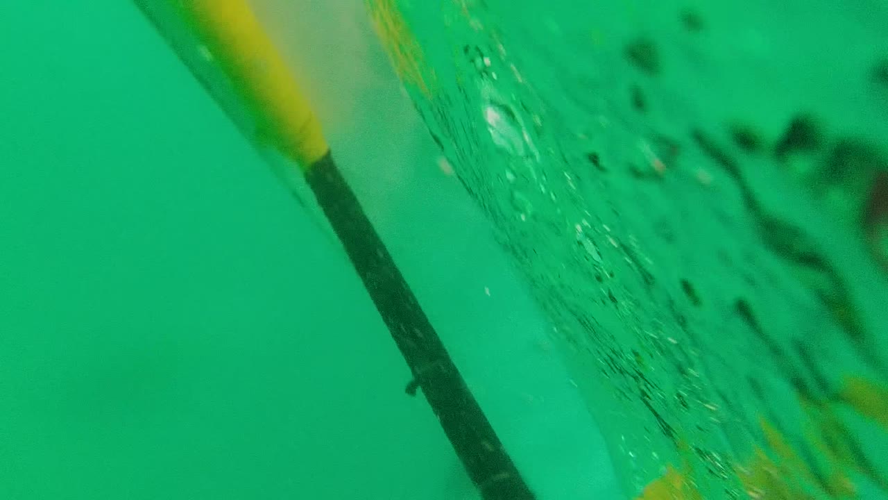 Underwater lane line and bubbles beside a swimmer.