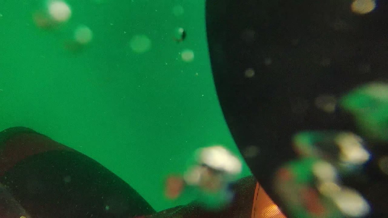 Blurred underwater view with partial diver gear and bubbles in green water.