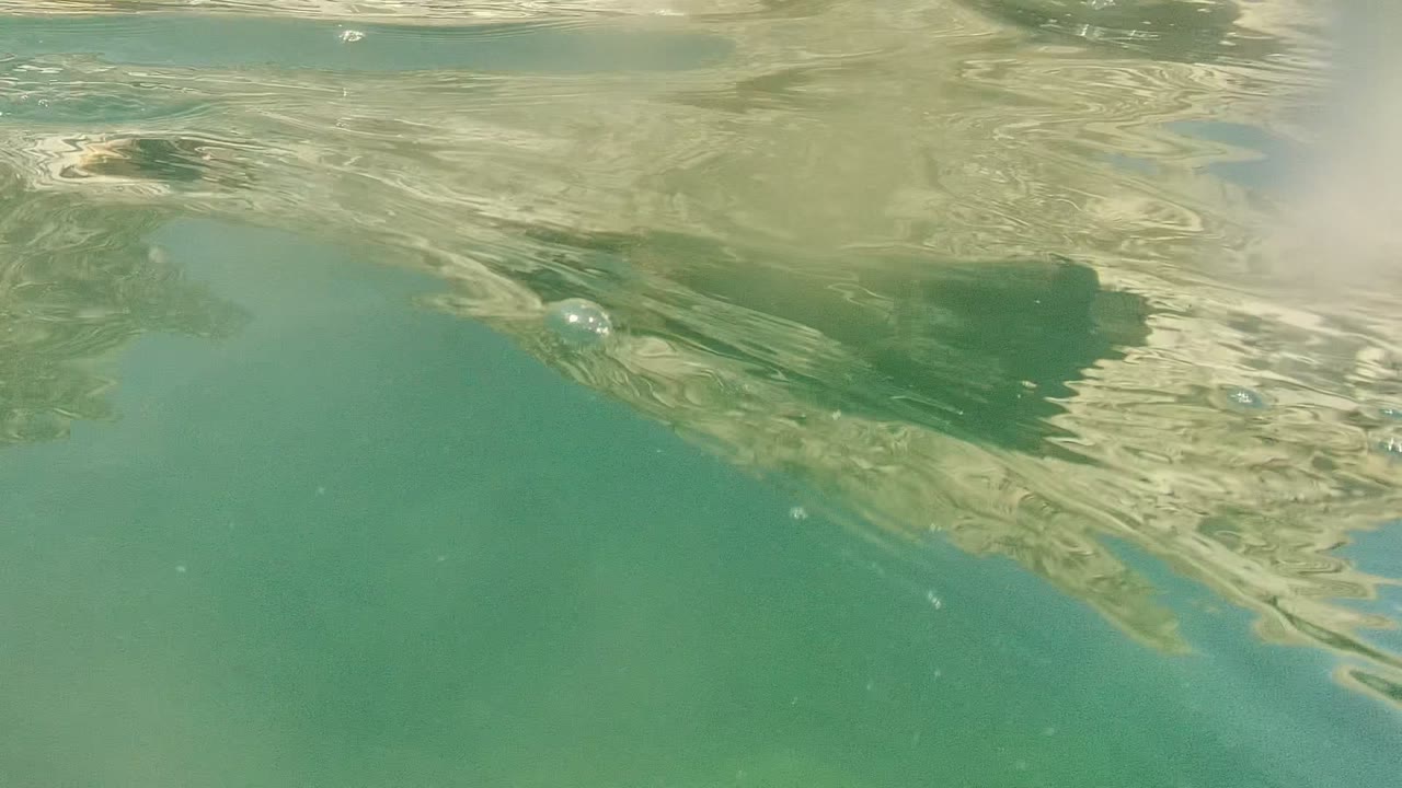 Turquoise underwater surface with bubbles and light reflections