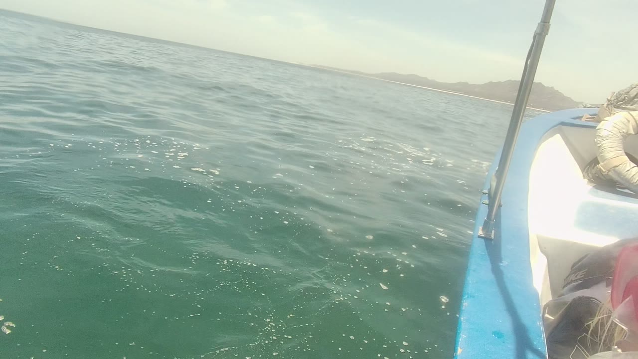 Ocean surface and small boat edge with distant land on the horizon.