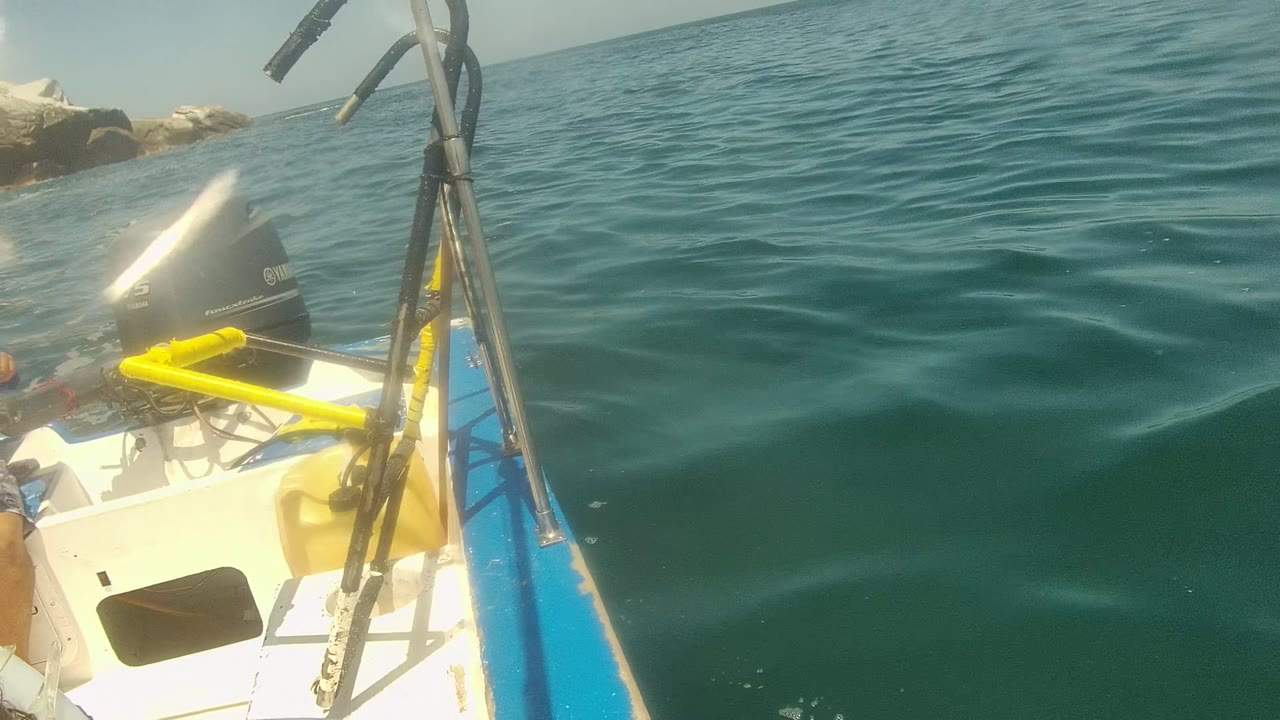 Boat deck and outboard motor beside rippling ocean water.