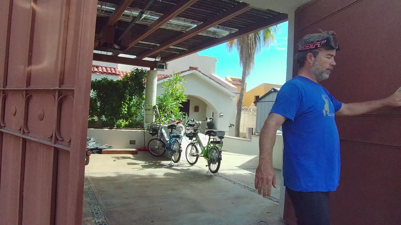 Courtyard with bicycles as a man holds the red gate