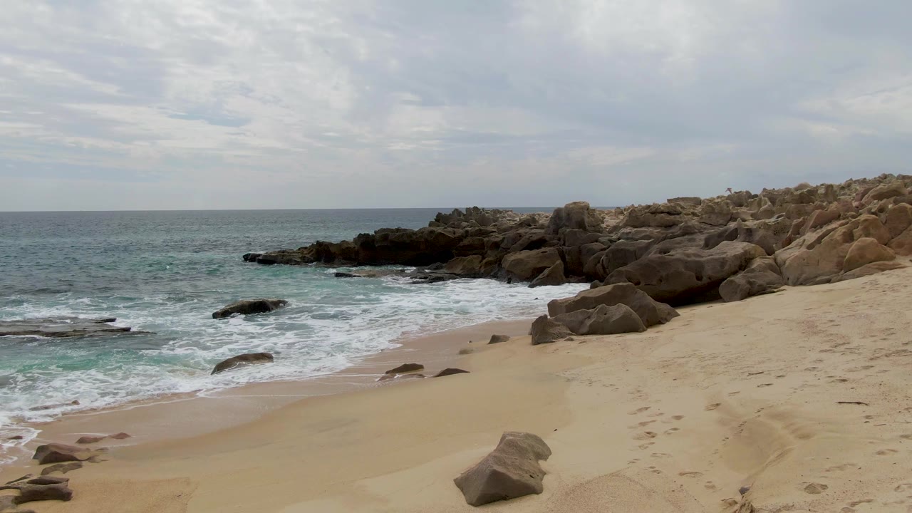 Surf washing around rocks on a sandy beach