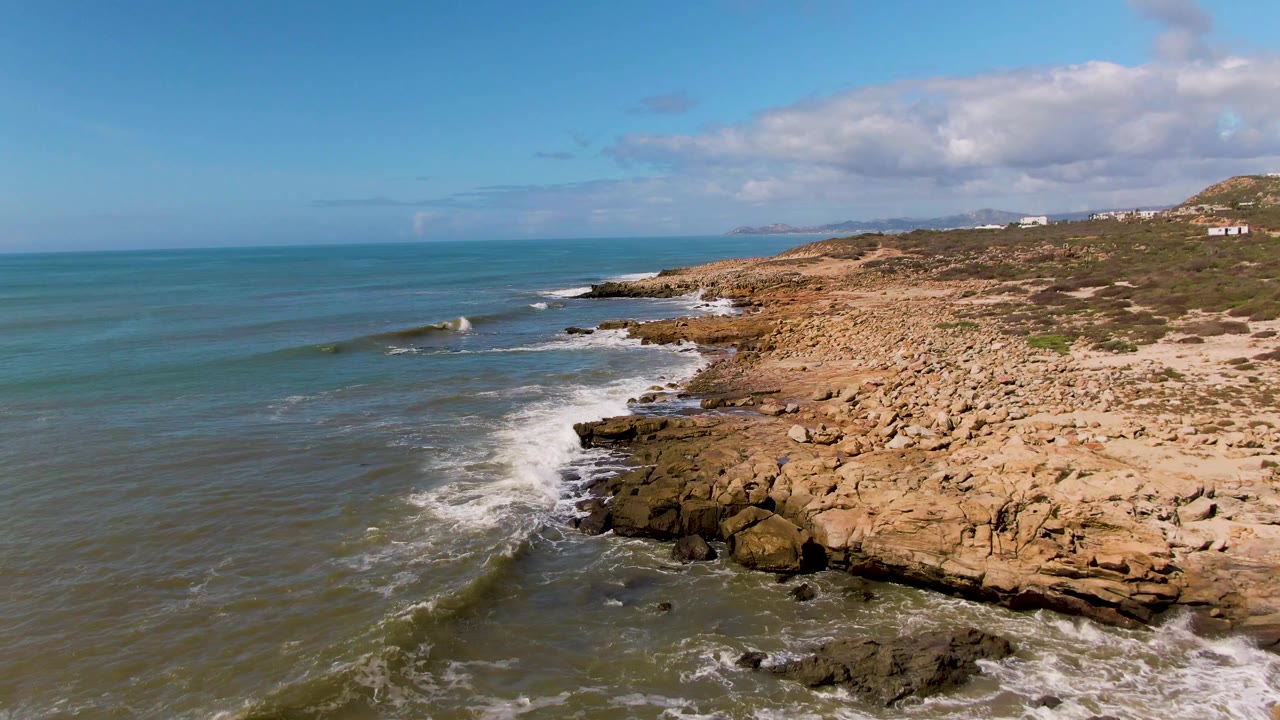 Waves curling toward a boulder-covered shore