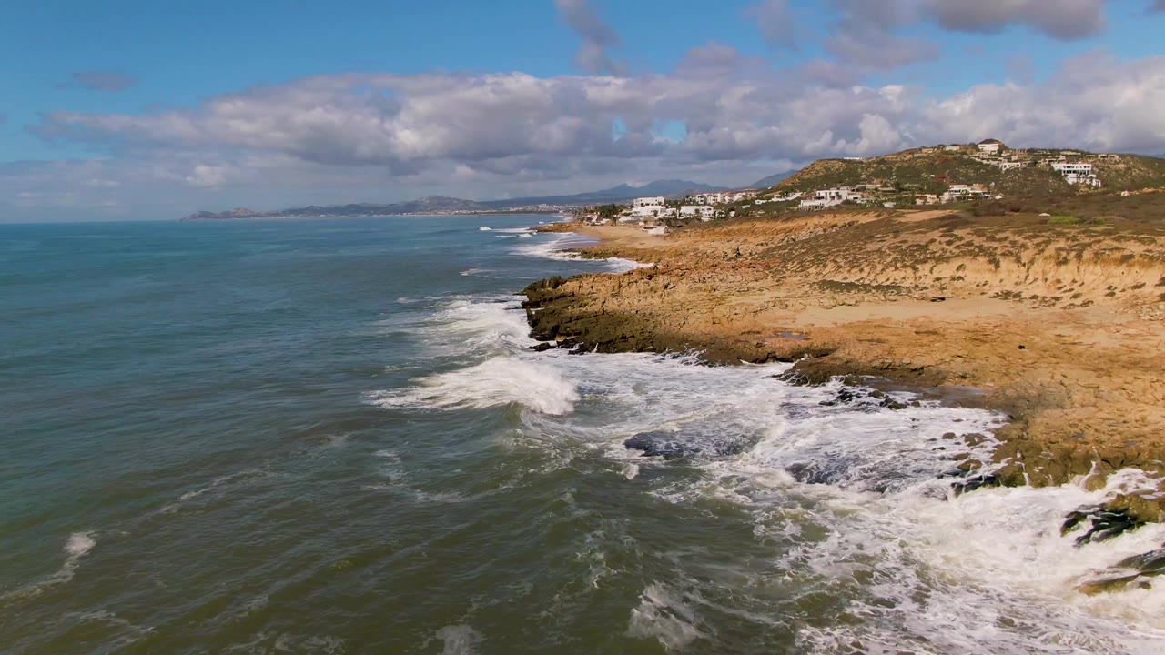 Aerial view of waves curling along rocky coastal edge