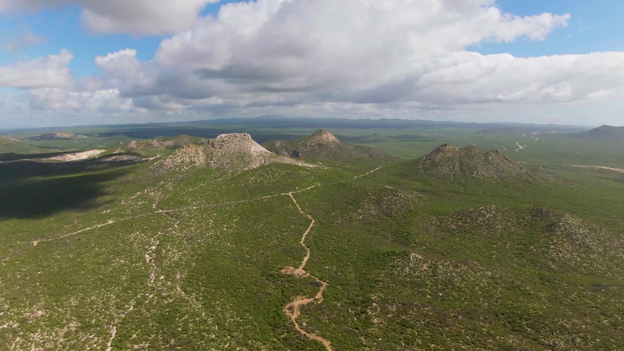 Wide aerial landscape with rocky hills and drifting cloud shadows