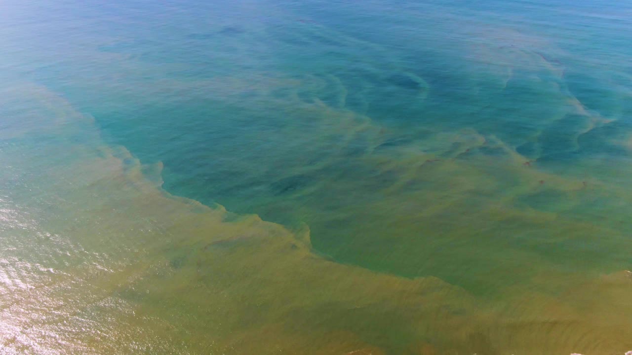 Turquoise and green ocean surface at Buzzards Beach East Cape BCS Mexico with soft current bands crossing the frame and no visible people.