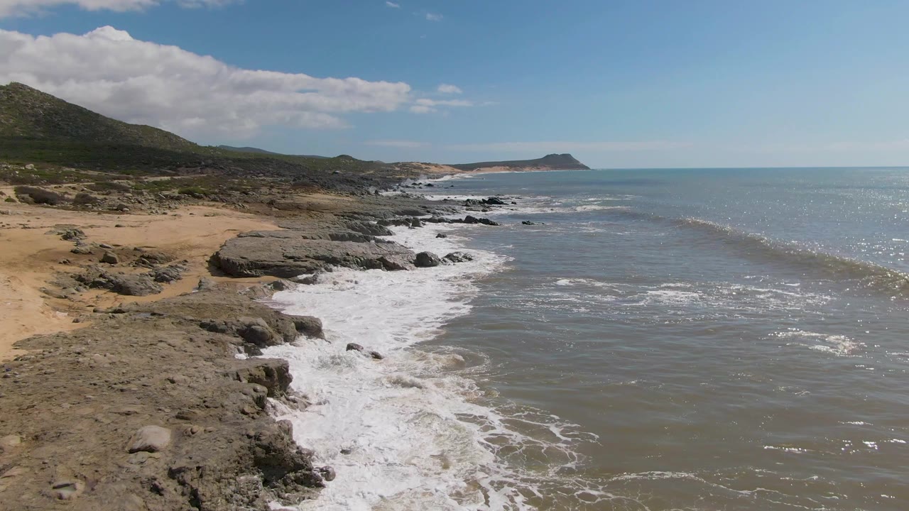 White surf washing over rocks along a tan beach