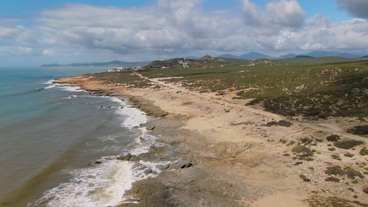 Wide aerial coast with waves breaking beside sandy beach