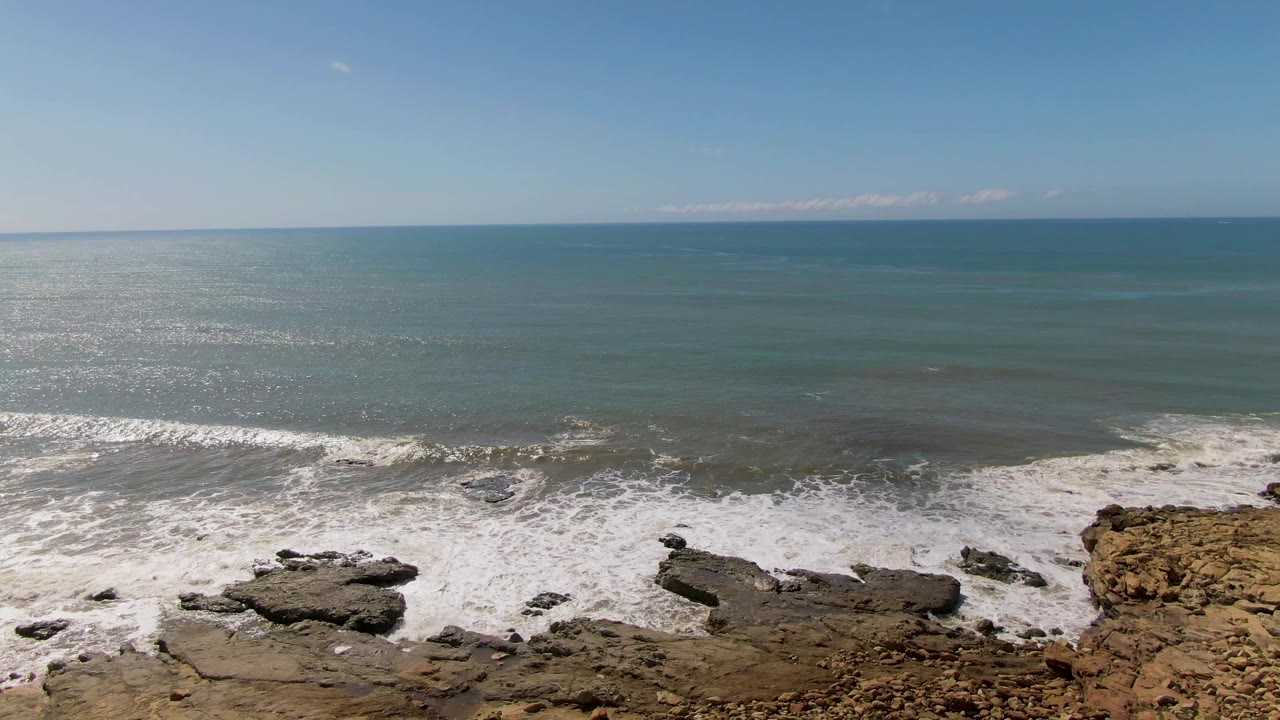 At 0:01, the surf line sits slightly farther across the flat rocks at Buzzards Beach, with blue-green water and no visible people in frame.