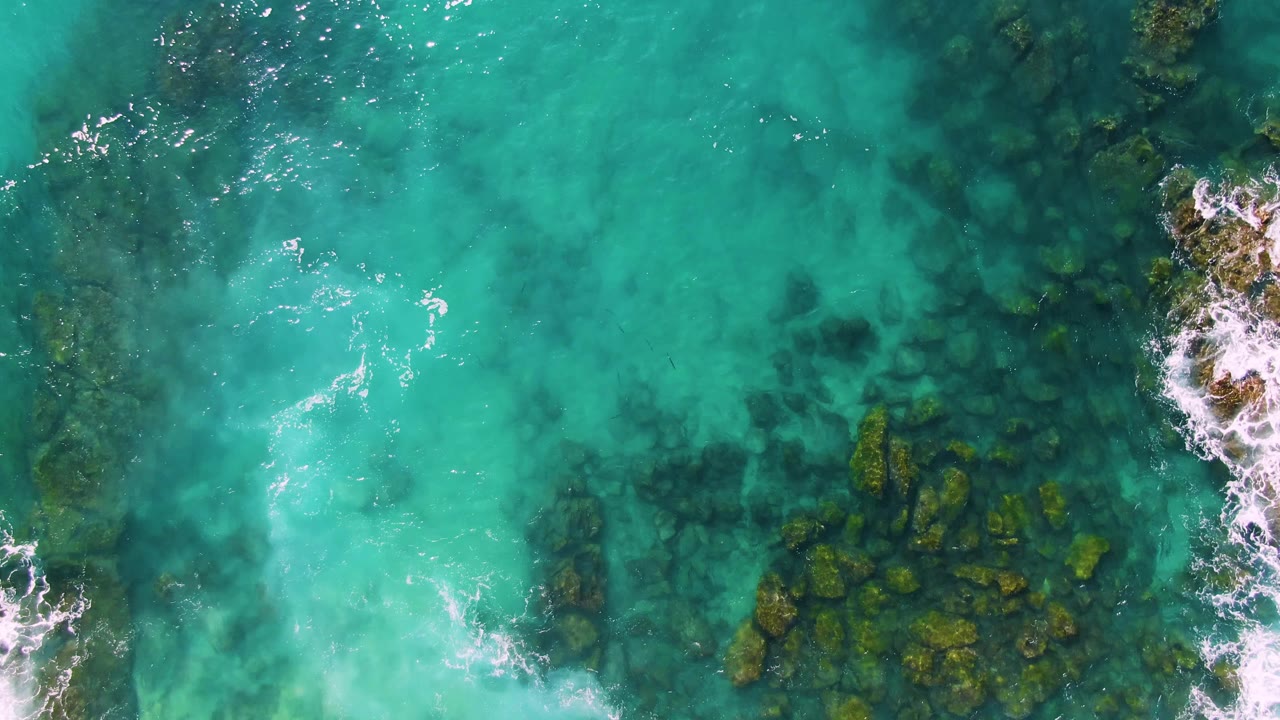 Overhead turquoise water with dark rocks and white foam